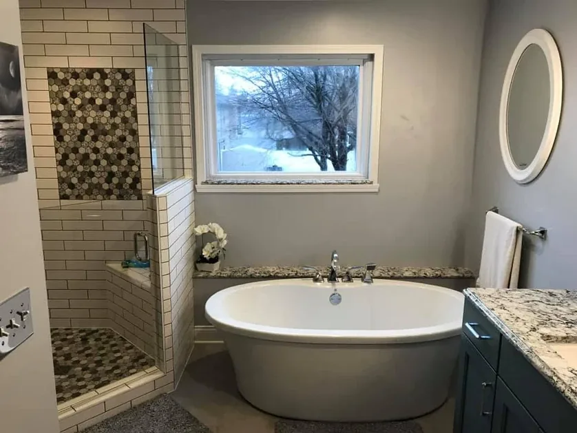 Bathroom with freestanding soaking tub and oval window by Padgett